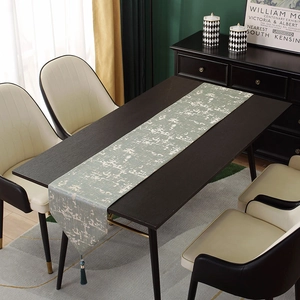 Detail of light grey-green jacquard table runner with abstract texture and green tassels