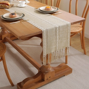 Bohemian style hollow woven table runner with tassels on a rustic wooden dining table