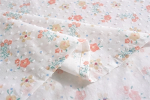 Macro detail of French cotton tablecloth with orange floral prints and Swiss dot texture