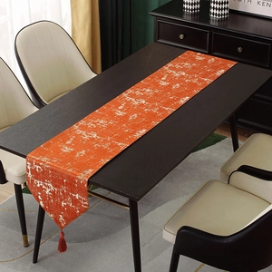 Close-up of orange luxury jacquard table runner with distressed texture and tassels