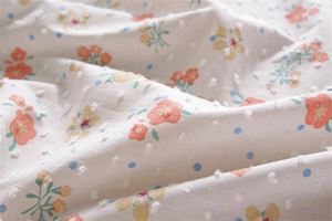 Detail of floral printed cotton fabric with elegant white tufted pom poms and Swiss dots