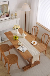 Detail of crochet lace table runner featuring beige wave patterns and boho tassel edges