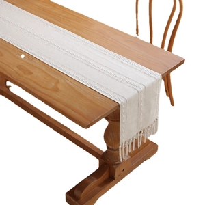 Boho cream white jacquard hollow table runner with elegant tassels on a wooden table