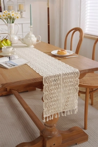 Close-up of cream crochet table runner showing hollow ripple patterns and tassels