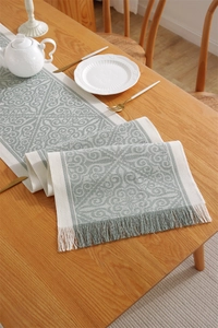 Detailed close-up of jacquard table runner with geometric leaf patterns and tassels