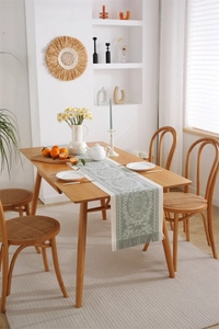 Detail of sage green jacquard table runner with white mandala pattern and tassels