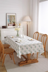Detail of floral printed cotton tablecloth with green leaves and red berries on a wooden table