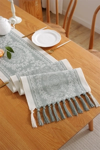 Detail of woven table runner with jacquard leaf patterns and handcrafted tassels