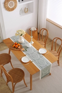 Detail of sage green jacquard table runner with white mandala pattern and tassels