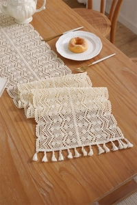 Close-up of cream crochet lace table runner with hollow geometric patterns and tassels