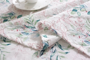 Detail of floral printed cotton tablecloth featuring Swiss dot texture and leaf patterns