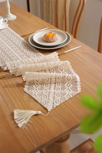 Close-up of vintage crochet lace table runner with tassels on a wooden dining table