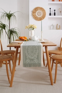 Detail view of light green jacquard table runner with mandala pattern and fringe tassels