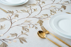 Detailed close-up of vine embroidery on premium linen tablecloth with elegant cutlery