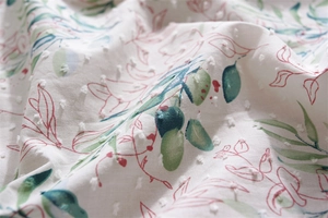 Close-up of cotton tablecloth fabric with dobby dots and green leaf floral pattern