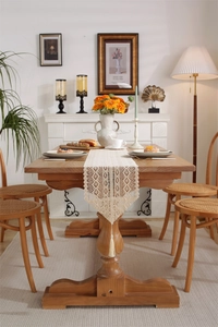 Detail of bohemian crochet lace table runner featuring fringe edges on a wooden table