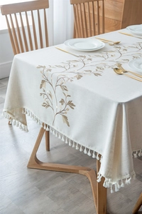 Detail of embroidered floral patterns and white tassels on a waterproof beige tablecloth