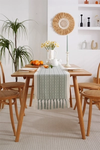 Detail of light green and beige geometric woven table runner with decorative tassels