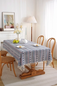 Detail of bohemian geometric tablecloth with delicate white tassel edges on wood table