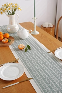 Close-up of geometric embroidered table runner with decorative tassels and dining setup
