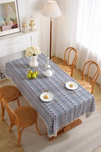 Detail of bohemian geometric tablecloth with white fringe tassels on a wooden dining table