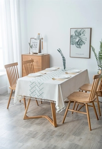 Close-up of Nordic woven tablecloth featuring green wave pattern and delicate white tassels