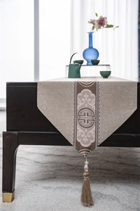 Detail of Chinese table runner featuring embroidered clouds and elegant tassels on wood