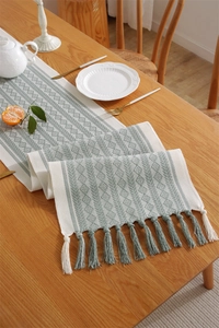 Detailed view of sage green and beige geometric jacquard table runner with fringe