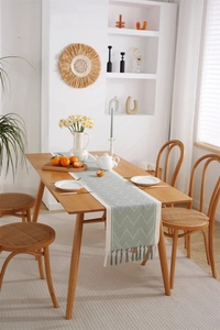 Detailed view of sage green and cream geometric jacquard table runner with fringe edges