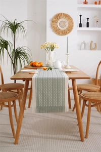 Close-up of a woven green and white geometric diamond table runner with tassel fringe