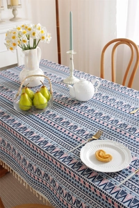 Detail of bohemian geometric tablecloth featuring white tassels and vibrant cotton fabric