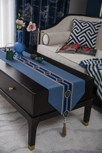 Close-up of blue table runner with yellow Greek key pattern and decorative tassels