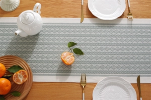 Detail of olive green woven table runner with geometric patterns and fringe edges