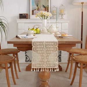 Beige hand-crocheted table runner with hollow geometric floral patterns and fringe