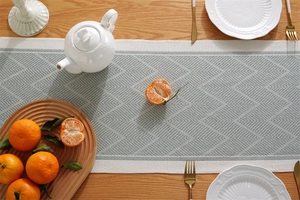 Detail of woven table runner with gray and beige geometric chevron patterns and tassels
