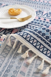 Macro detail of Bohemian geometric tablecloth with white fringe and tableware setup