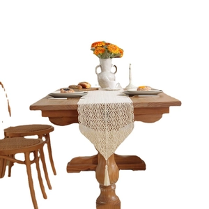 Retro hollow-out crochet table runner with lace floral pattern and tassels on wood table