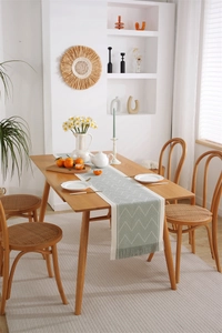 Detailed view of sage green herringbone jacquard table runner with delicate long tassels