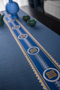 Detail of navy blue table runner with golden circular patterns and wave trim