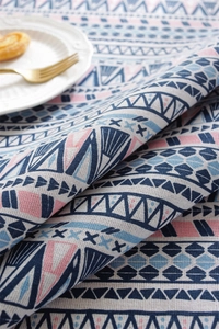 Detail of bohemian geometric tablecloth fabric featuring navy blue and pink woven patterns