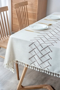 Detailed close-up of embroidery pattern and cotton fringe on linen tablecloth