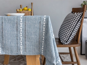 Close-up of white floral embroidery and openwork hollow detail on blue jacquard tablecloth
