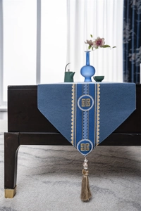 Detail of blue Chinese table runner with gold geometric patterns and luxury tassels