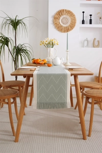 Detail of grey-green and white woven jacquard table runner with handmade fringe tassels