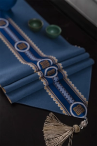 Detail of dark blue table runner with yellow embroidery and large beige tassel