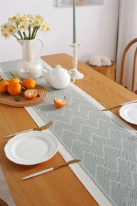 Detail of grey-green geometric jacquard table runner with textured woven fabric