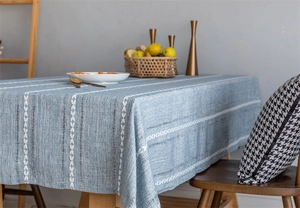 Detail of blue jacquard tablecloth with white geometric embroidery on a wood table