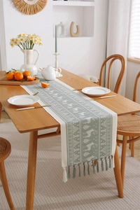 Close-up of Nordic jacquard table runner with elk motifs and handmade tassel details