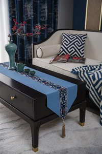 Detail view of sky blue table runner featuring intricate embroidery and silk tassels