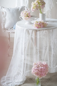 Detailansicht der weißen floralen Stickerei und Rüschenspitze an der Netztischdecke